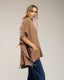 Poncho de punto con flecos en los laterales, cuello perkins y bolsillos.