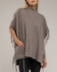 Poncho de punto con flecos en los laterales, cuello perkins y bolsillos.
