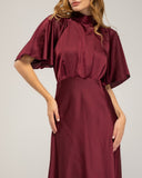 Long satin dress with a turtleneck and bow at the back, fitted at the waist with short flared sleeves