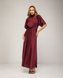 Long satin dress with a turtleneck and bow at the back, fitted at the waist with short flared sleeves