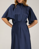 Long satin dress with a turtleneck and bow at the back, fitted at the waist with short flared sleeves